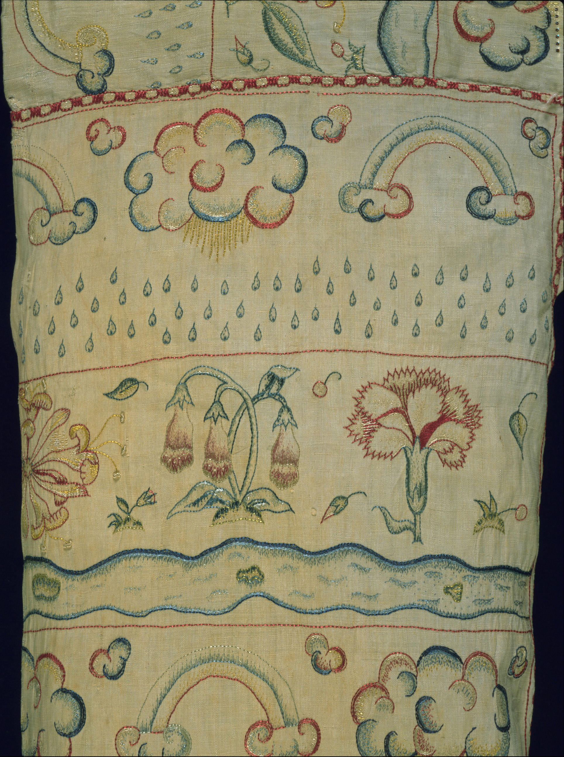 Title: Woman’s smock Place:England Date: c. 1600 Medium & technique: Linen, hand-embroidered with coloured silks Dimensions: 40 x 1390 mm (bodice and sleeves) Themes: Bodies - Inside & Outside Collection: (c) the Whitworth, The University of Manchester The embroideries shown in this detail – featuring carnations, foxgloves and honeysuckle – decorate an early-seventeenth-century woman’s smock, or shift. Originally full length, only the patterned bodice and sleeves have survived and it is likely that the owner cut off the plain, lower half of the garment after the linen became marked or damaged. One of the functions of an undergarment like this smock was to draw sweat and impurities away from the body and various contemporary authors mused on the consequences of wearing dirty or clean linens. From sweet-smelling flowers to a shower of raindrops and clouds anticipating a storm, the embroideries on the smock remind us of the influence of the environment on the body and the role of this garment in shielding the wearer from the hazards of bad air and excess heat or cold. Elizabeth Currie, Victoria and Albert Museum/ RCA